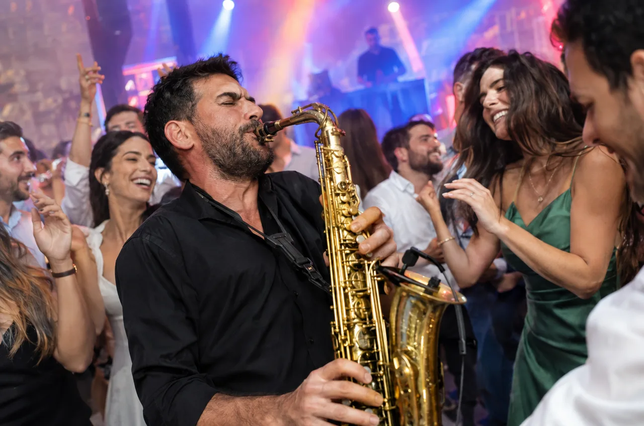 שילוב של זמר ודיג'יי בחתונה עם סקסופוניסט על רחבת הריקודים