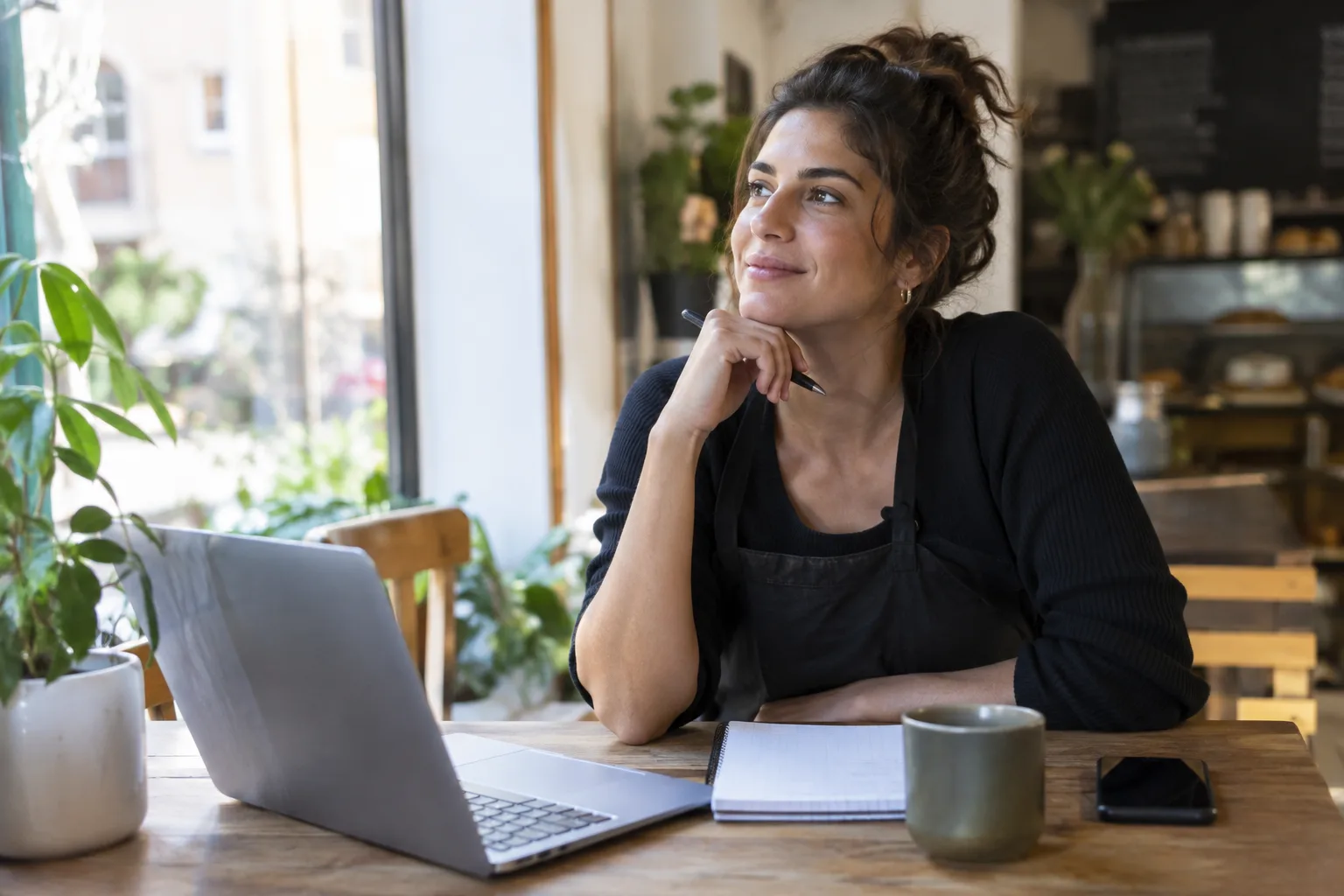A small business owner sits at a desk, planning their social media content calendar on a laptop.