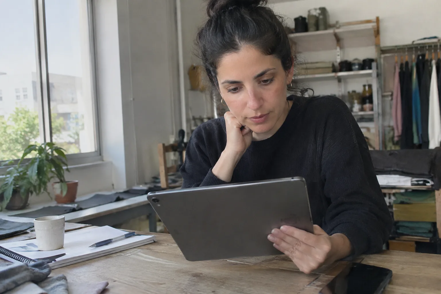 בעלת עסק קטן בוחנת דוגמאות למודעות וידאו ממומנות על טאבלט במשרד שלה.